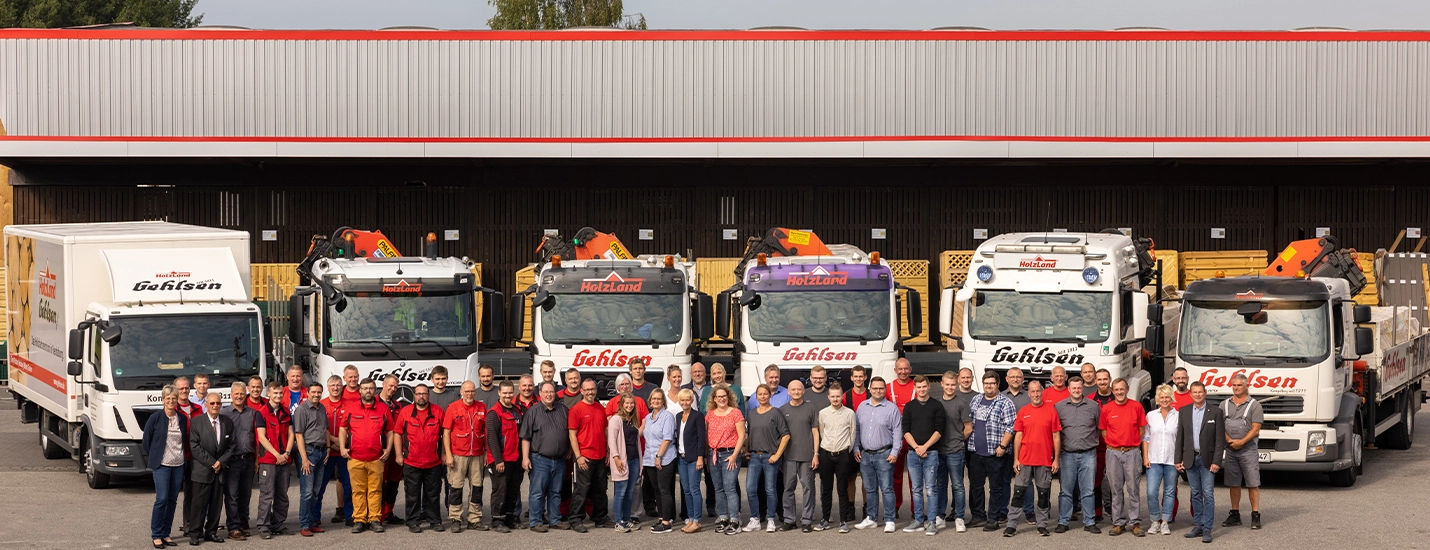 Gruppenbild der Holzland Gehlsen Mitarbeiter vor Fuhrpark und Lager