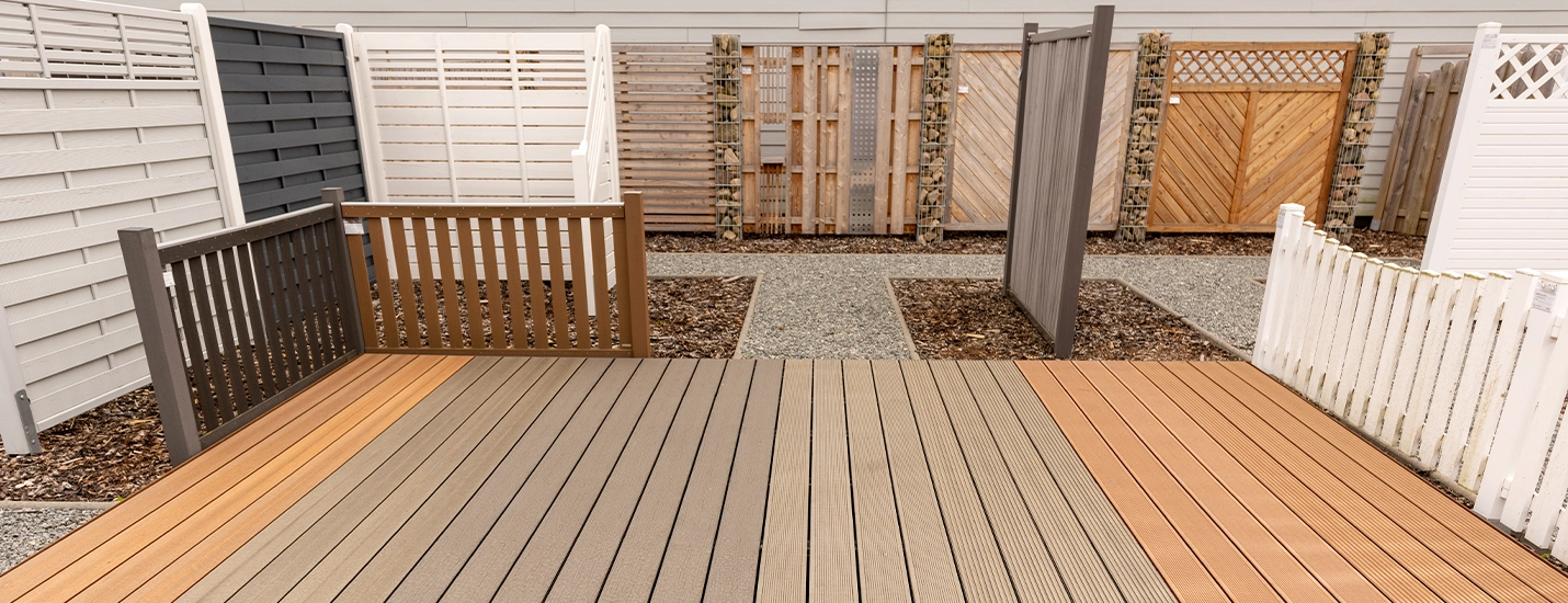 Ausstellung verschiedener ausgelegter Terrassendielen im Außenbereich mit Sichtschutzzäunen im Hintergrund